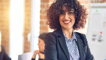 Smiling person with curly hair in office setting.