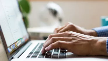 Person typing on a laptop with a blurred background.