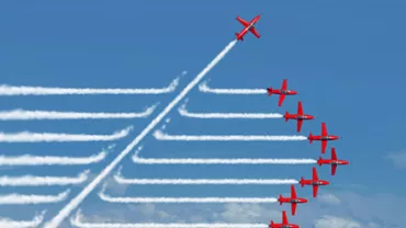 Formation of red planes with trails in the sky, one diverging upwards.