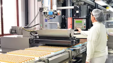 Worker operates a candy production machine in a factory setting.