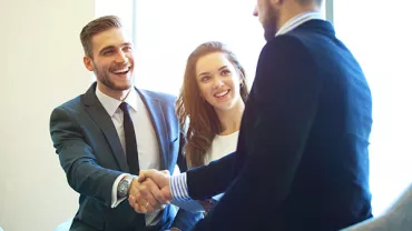 Smiling professionals shaking hands in an office setting.