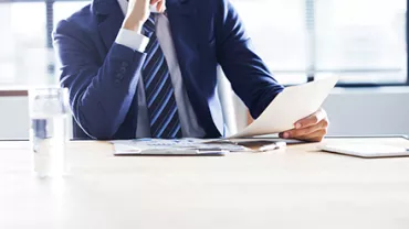 Businessman in a suit analyzing documents at a desk.