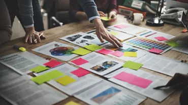 People brainstorming with documents and sticky notes on a table.