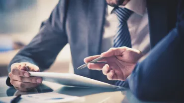 Two people in suits reviewing a document at a desk.