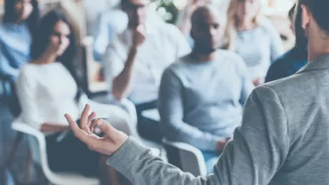 Person giving a presentation to a diverse group of people in a casual setting.