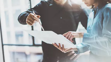 Two people discussing a document in a bright office setting.