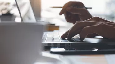 Close-up of hands typing on a laptop keyboard.