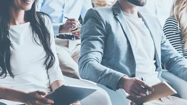 Smiling people sitting in a meeting taking notes.